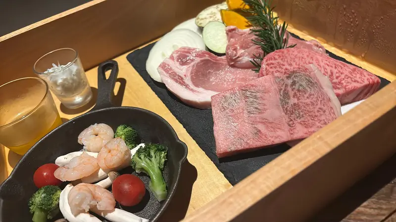 スレートに盛られた、美しいサシの入った淡路牛と厚切りのポーク。手前のスキレットには海老と彩り野菜