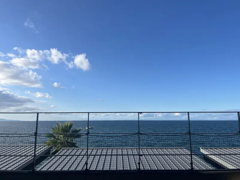 SolaVilla 海テラス南あわじのテラスから望む播磨灘。青空と水平線、沖に小さな漁船が浮かぶ
